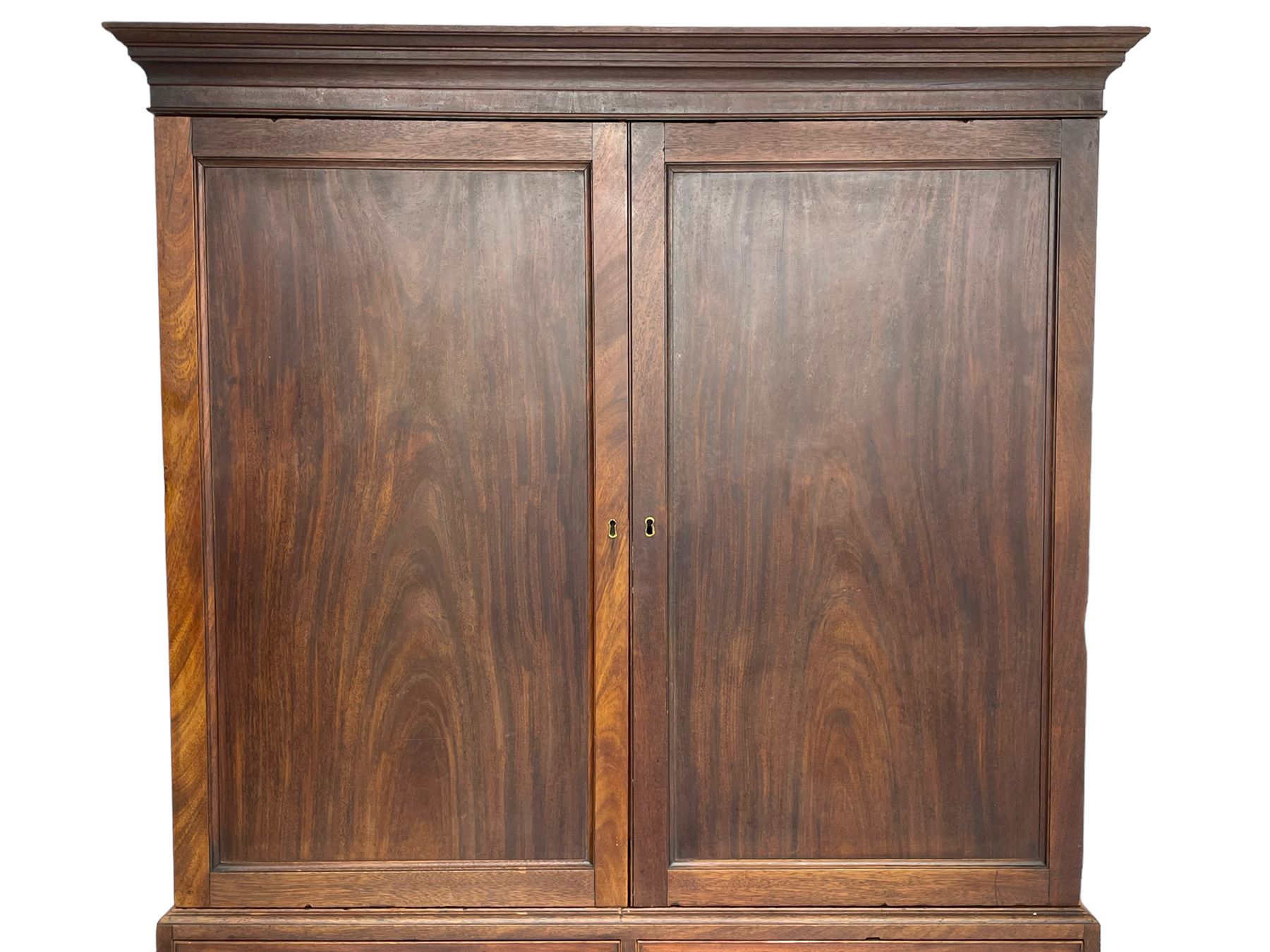 George III mahogany Gentleman's linen press, the projecting cornice over two panelled cupboard doors enclosing three sliding trays, the base fitted with two short over three long graduating cock-beaded drawers, lower moulded edge over bracket feet