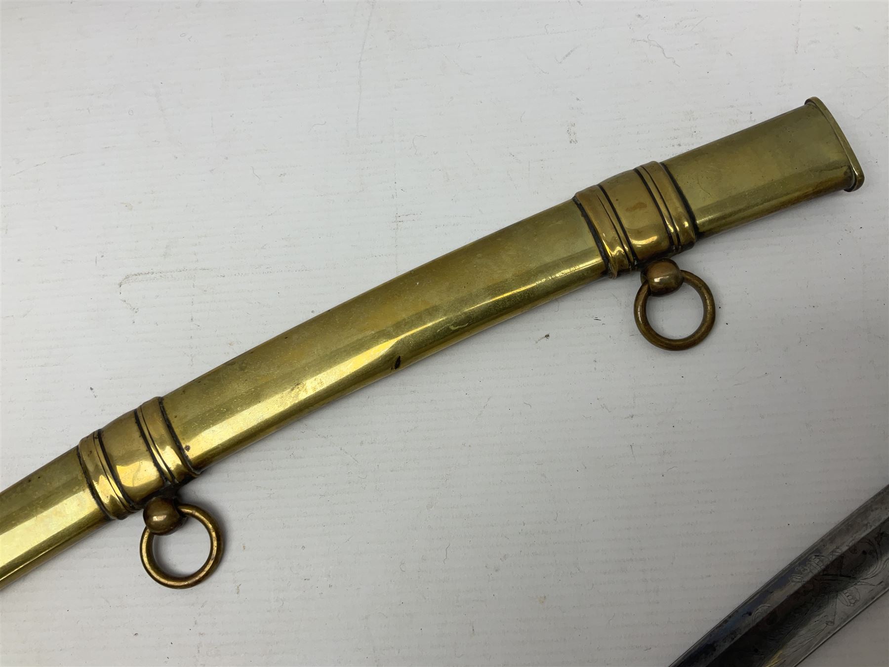 German Saxon 1st Empire Light Cavalry officer's sword c1820s, the 79cm clipped curving blade engraved with the crest of Hanover and various battle trophies with traces of blueing and gilding, brass hilt with knucklebow, foliate square langets, ornate downswept quillon, wire-bound fish skin grip with lion's head pommel; in brass scabbard with two suspension rings L95cm overall