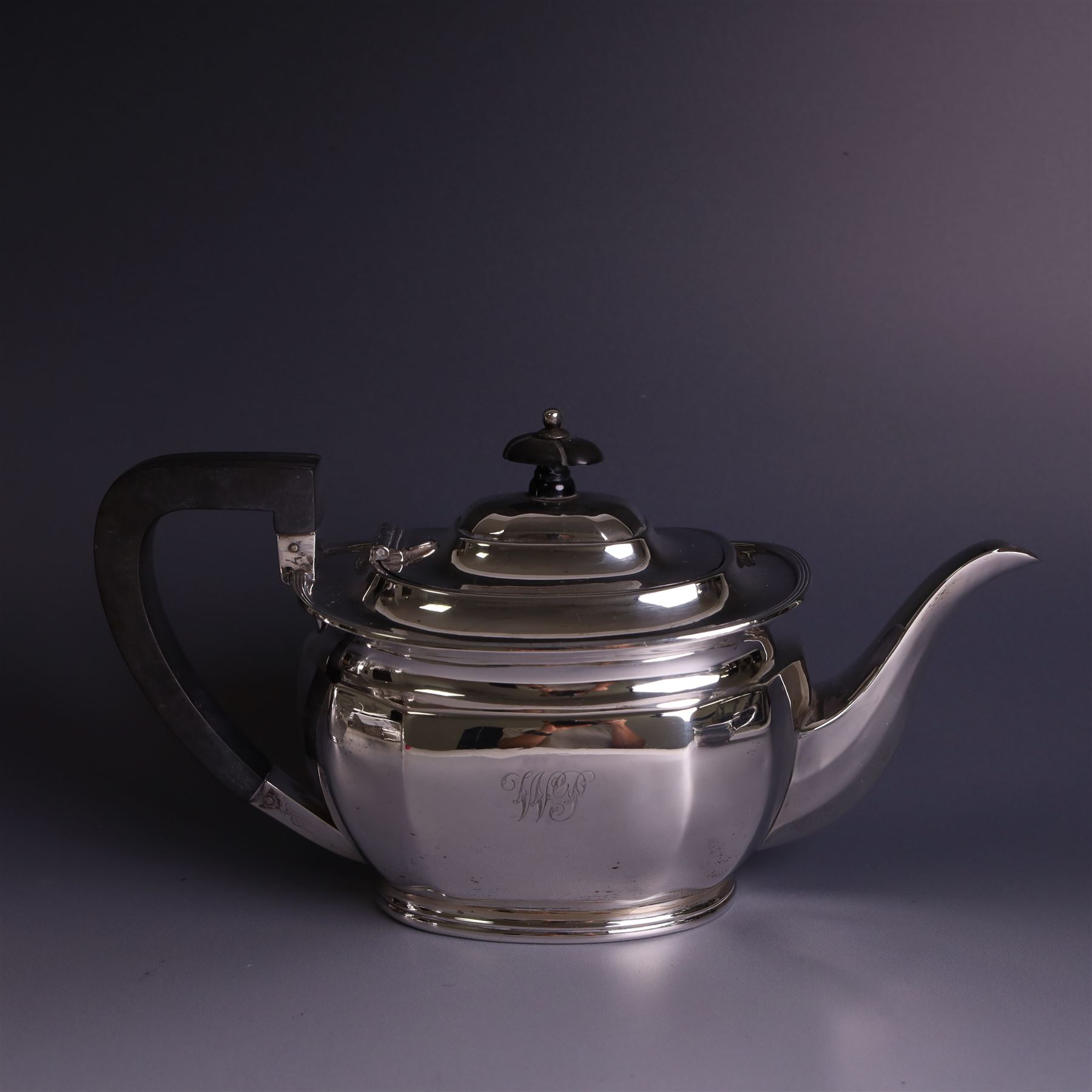 1930s silver four piece tea service, comprising teapot, hot water pot, sugar bowl and milk jug, each of part faceted oval form with engraved monogram to body, the teapot and hot water pot with Bakelite type handles and finials, hallmarked Atkin Brothers, Sheffield 1933