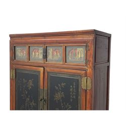 Late 19th century Chinese Qing dynasty red and black lacquered wood cabinet,  Fujianese province, upper cupboard enclosed by two doors with relief carved and gilt panels depicting figures behind glass, the large cupboard enclosed by two panelled doors carved with trailing foliate branches and birds, inscribed with Chinese characters, to the left ‘The red mountains are in the shape of Phoenixes and appear auspicious’ and to the right, ‘Wealth and honour are given by flowers and I hear the sound of the phoenix', fitted with two drawers, on square supports with carved brackets 