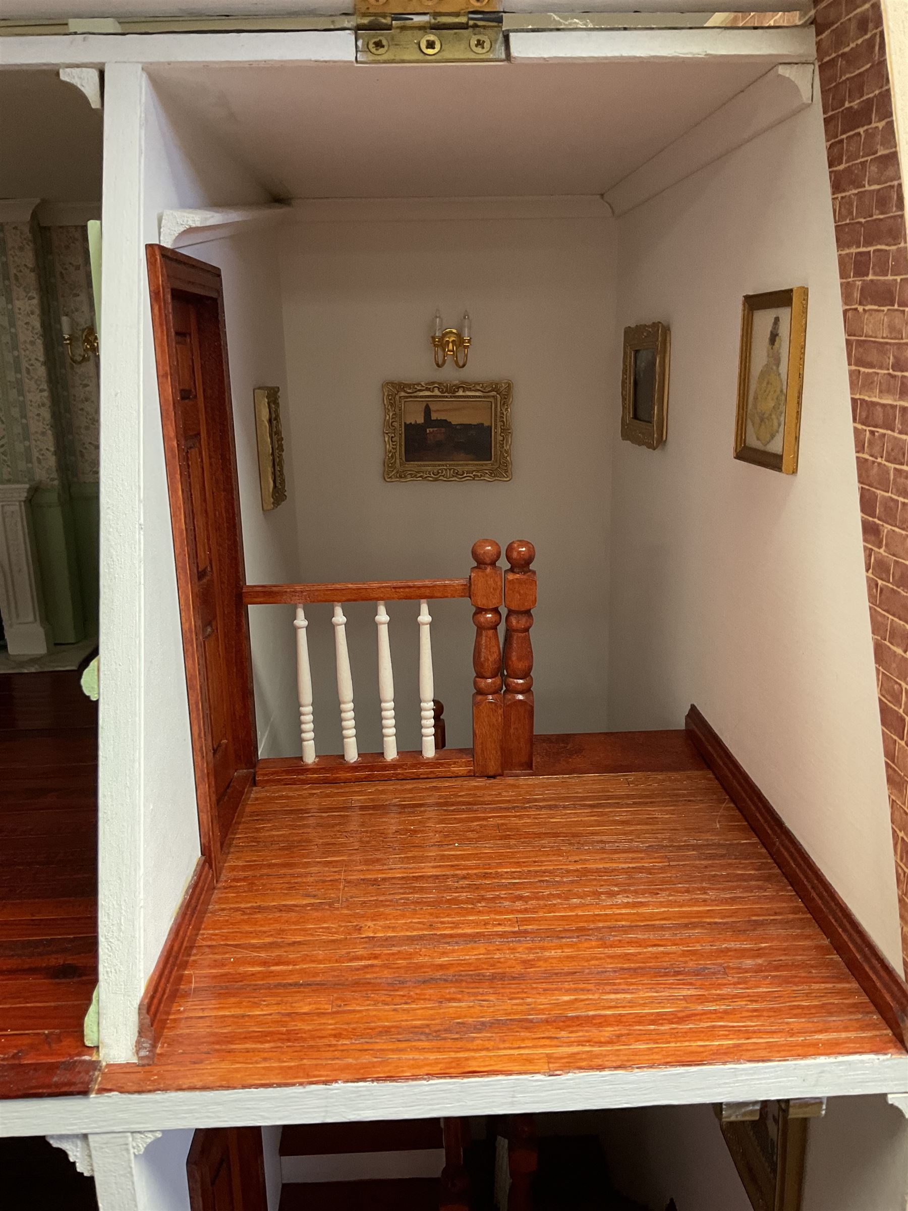 'The Hollies' - good quality sectional wooden doll's house in the form of a Georgian style four-storey bay windowed town house with simulated brick front elevation, rendered sides, off-set corner stonework, faux slate-hung top floor with flat roof and chimney stack, working sash windows, iron railings around front basement courtyard with hinged front elevation to two rooms with  spiral staircase, side hinged central section approached by external steps with iron balustrades to the sides leading to a front door, entrance hall with stairs to landing and two rooms on two floors with dado panelling and fire-surrounds, the top floor with top hung front elevation revealing stairs to a landing and bedroom; wired for electricity L51cm D65cm H107cm including chimney; together with a good quantity of quality wooden furniture and accessories including piano, dressers, bookcase and books, rugs, double half-tester bed, metalware, pictures etc