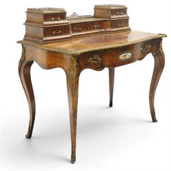 Victorian figured walnut and kingwood-banded ladies writing table, the raised superstructure with three-quarter pierced brass raised gallery back, fitted with five assorted drawers, the serpentine shaped top with oval inset leather surface, the bronze edge of egg and dart form with cartouche corners, fitted with central frieze drawer with inset Sevres-style floral ceramic plaque, raised on cabriole supports with gilt metal mounts