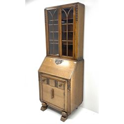 Early 20th century carved oak bureau bookcase, two glazed cupboard doors revealing adjustable shelving, fall front writing desk revealing fitted interior, above one short drawer and single cupboard door, turned ball supports and sledge feet