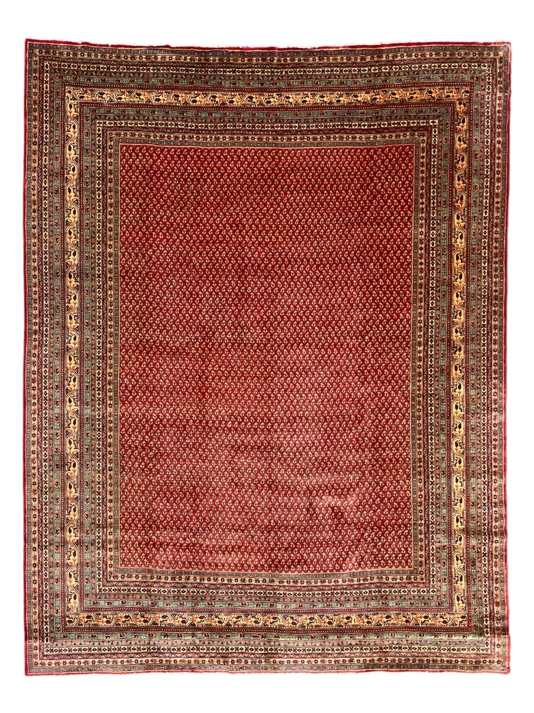Persian Arak crimson ground carpet, the field decorated profusely with small repeating Boteh motifs, enclosed by multiple border bands decorated with repeating geometric and hook motifs