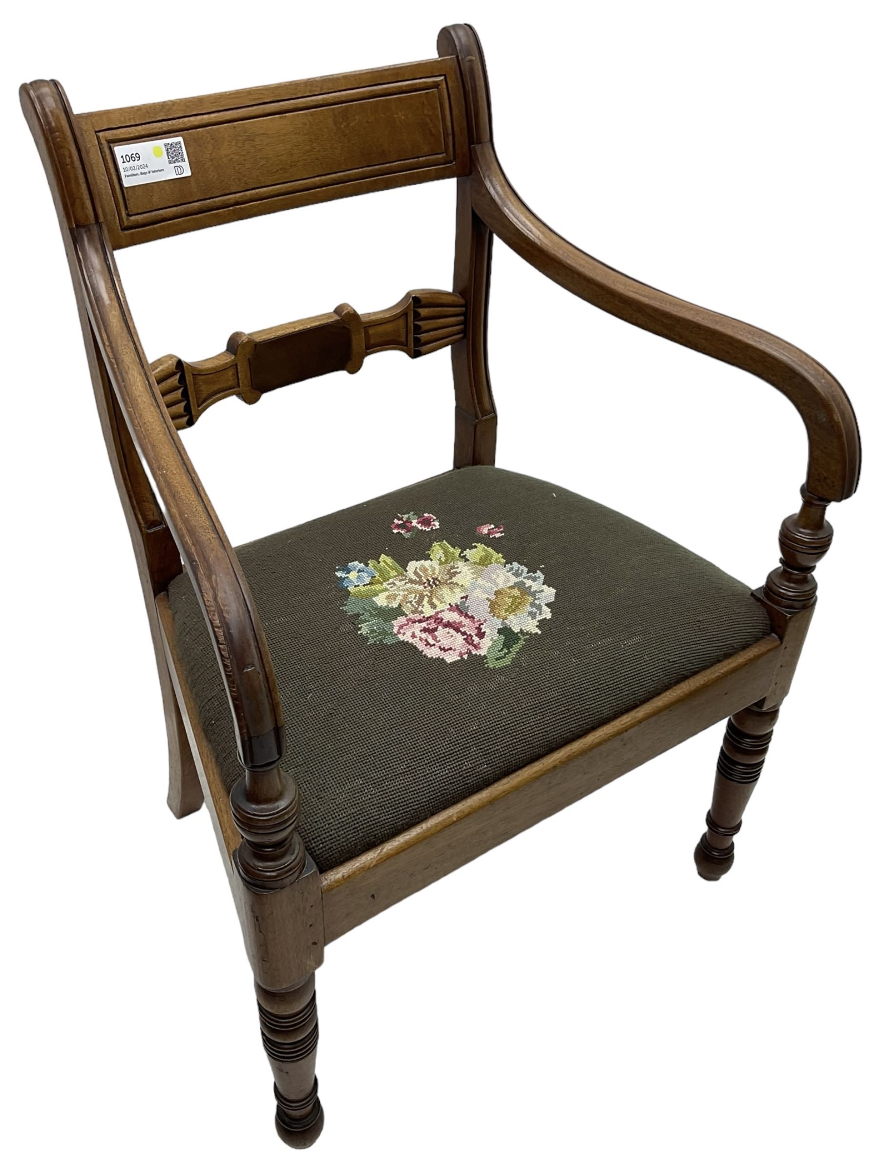 Regency mahogany elbow chair, carved shaped central back bar, over drop-in seat upholstered in floral needlework, raised on ring turned front supports