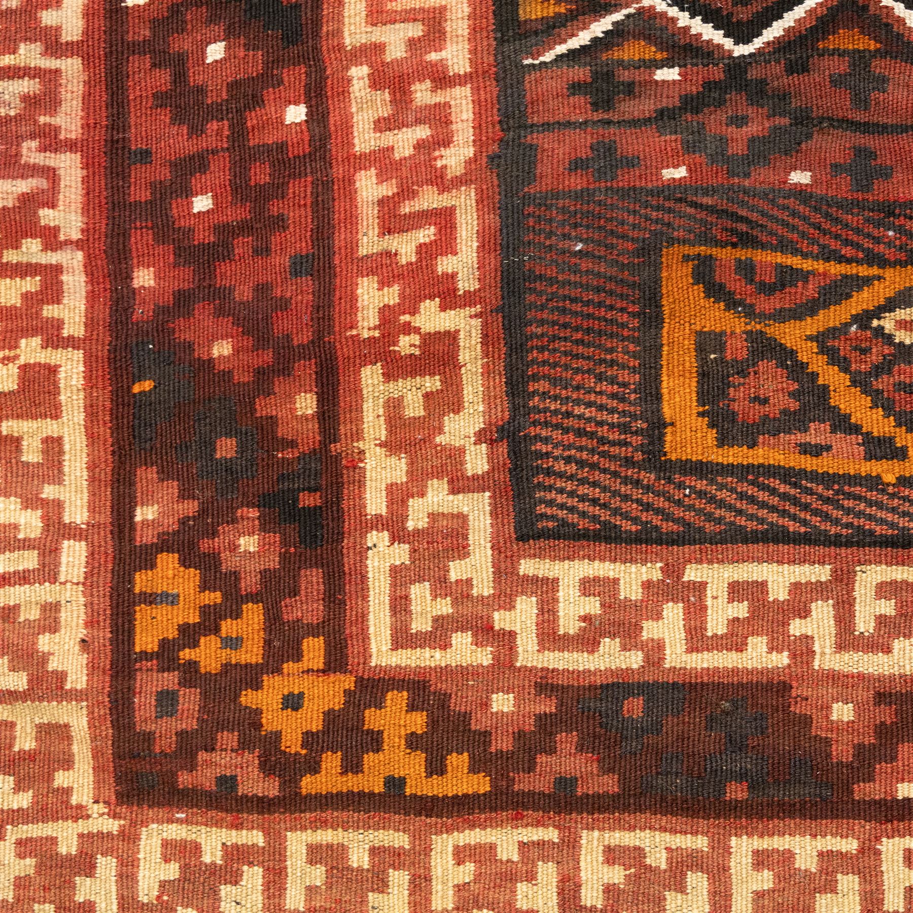North west Persian Yamut Kilim, madder field with all-over lozenge lattice and serrated edges, with stepped end-panels and bold geometric borders in red, ivory and black