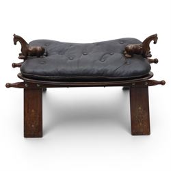 20th century saddle stool, wiht black leather seat, surmounted with carved horses, on an X-frame base with brass inlay