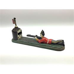 Very rare 19th century John Harper & Co. mechanical cast-iron money box, registered number 33821 patented 1885, inscribed on metal plaque 'Wimbledon Bank', based on the Queen's Trophy for shooting at Wimbledon, depicting a British Infantry man in red tunic and blue trousers lying on the ground using a gun to fire a brass coin launcher into a pill box with removable moving flag above L30cm