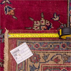 Large Persian-style mahal-type hand-knotted carpet, of rectangular form with a deep crimson field decorated with an all-over arrangement of stylized floral sprays and palmettes, with a central subtle medallion composition enclosed by a dark navy main border of scrolling floral motifs between narrow guard stripes with fringe ends 