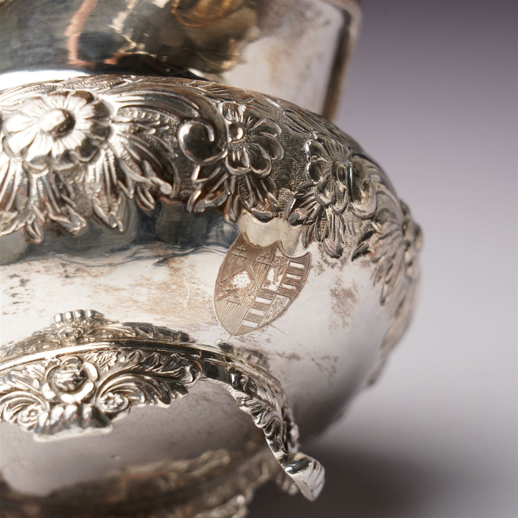 Matched three piece silver tea set comprising teapot of squat circular form London 1827,  milk jug of similar date and sugar bowl with Britannia standard marks, all with later embossed floral decoration and coat of arms, all marks rubbed