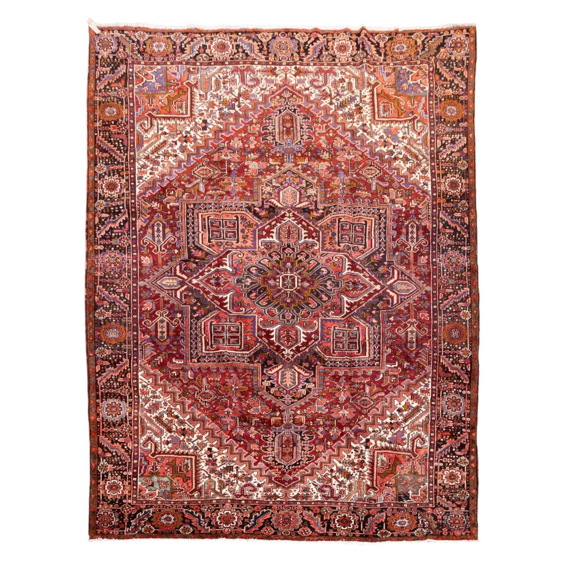 North West Persian Heriz hand-knotted carpet, brick red field, with large central angular star medallion with stepped outlines, surrounded by geometric floral devices and stylized rosettes, with corresponding corner spandrels, enclosed by a bold geometric main border with multiple guard stripes, with cotton fringe ends 