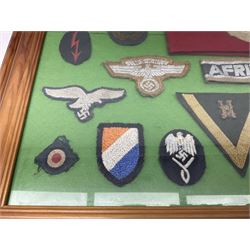 Framed display of thirty-four WWII German cloth badges including Luftwaffe pilot, Paratrooper, Afrikakorps cuff title, sleeve insignia for 'SS' Foreign Volunteers, various breast eagles including Luftwaffe, Army etc, RAD badges, Party Armband, rank and trade insignia, cap insignia etc; 40 x 50cm in modern pine frame