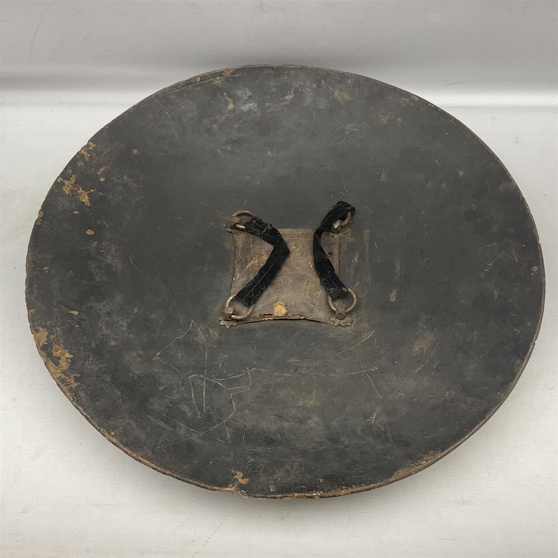 Indian black lacquered hide shield/dhal, of circular convex form fitted at its centre with four pierced iron bosses, each of hemispherical form with wide brims, the bosses corresponding on the inside with four iron rings for enarmes D53.5cm