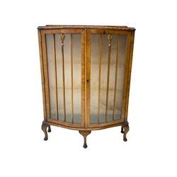 Early 20th century walnut serpentine display cabinet, two glazed doors enclosing glass shelves, raised on cabriole supports