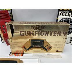 Three late 70s/early 80s handheld electronic games; Bandai Electronics Arcade ‘Gunfighter’ (1980), Grandstand ‘Invader From Space’ (1980), Palitoy ‘Merlin The Electronic Game Machine’ (1979) with game sheet and instruction booklet, all with original boxes (3) 