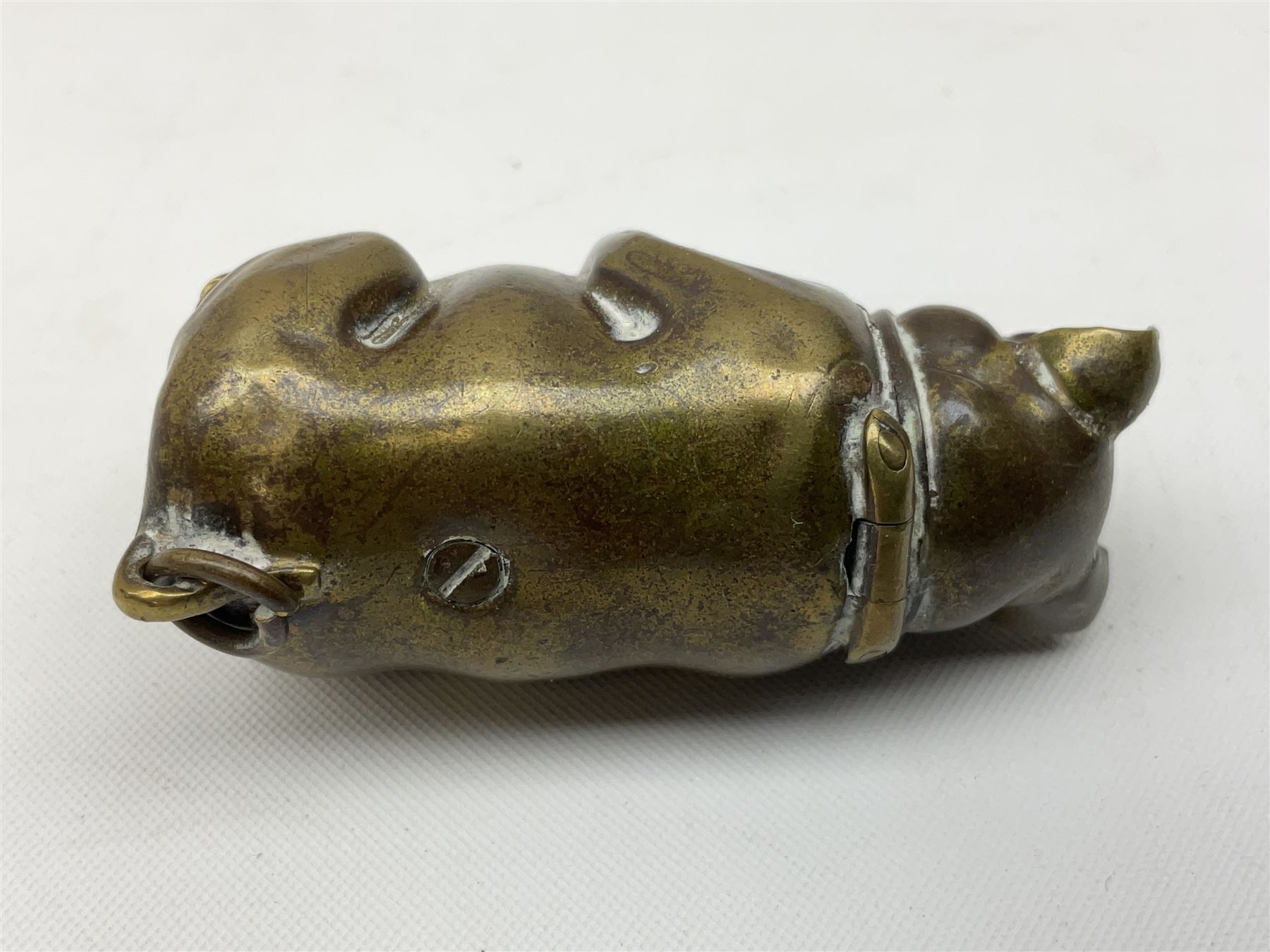 Victorian novelty brass vesta case modelled in the form of a pig holding a money bag, together with a silver vesta, hallmarked 