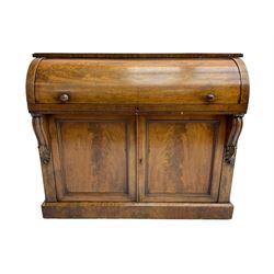 Victorian mahogany roll-top writing desk, top concealing fitted interior with pigeonholes and three drawers, the trisector inset writing surface with writing slope, base fitted with panelled cupboard enclosing single shelf, decorated with scrolled corbels