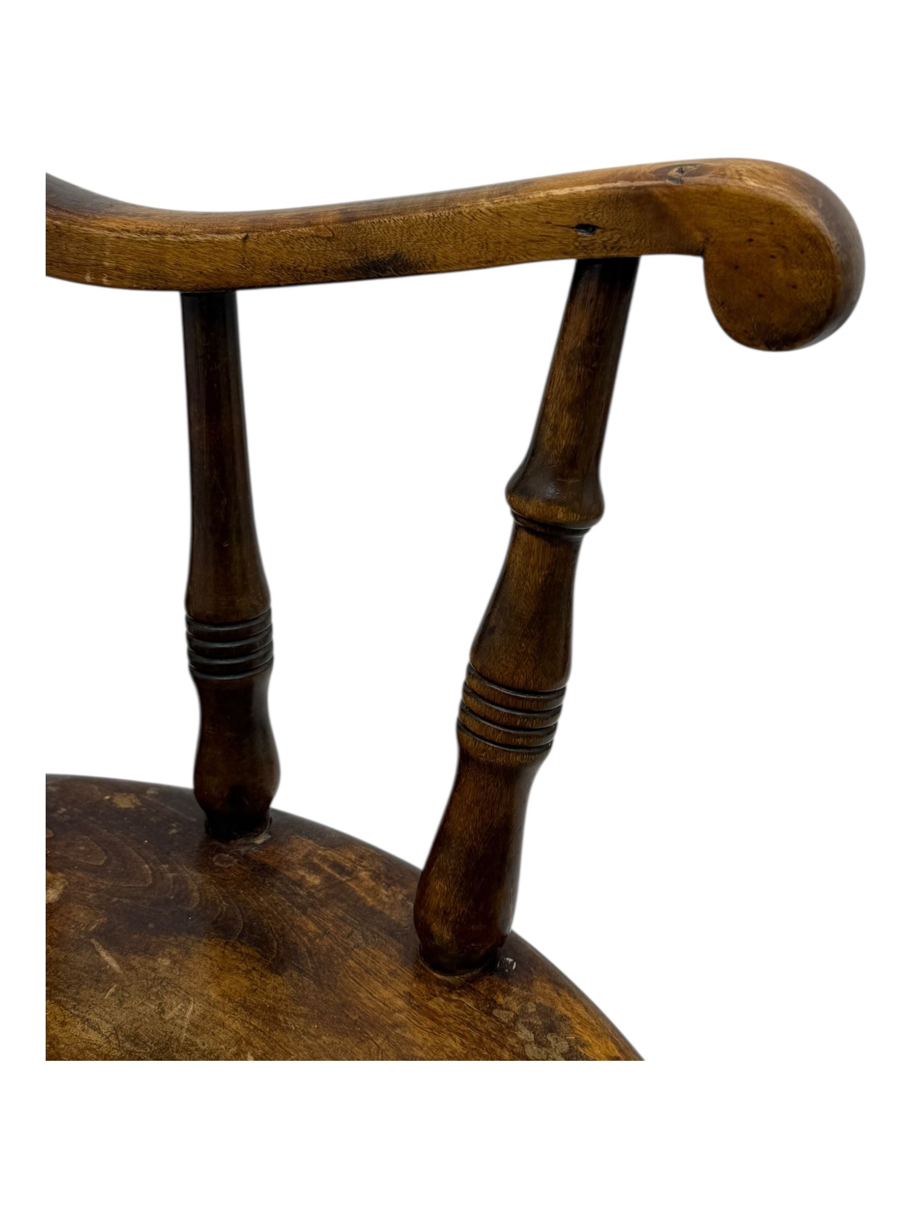 Late 19th century elm and beech Windsor rocking chair, with shaped top rail over turned spindles and curved arms, circular seat raised on turned legs united by stretcher on rockers