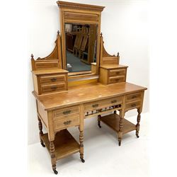 Edwardian ash dressing table, raised mirror back with dentil frieze, nine drawers, turned supports on castors 