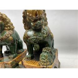 Pair of Chinese Temple Lions or Dogs of Foo, modelled in seated post, one with one front paw resting upon a ball, the other upon a cub, each upon stylised plinth base, H44cm