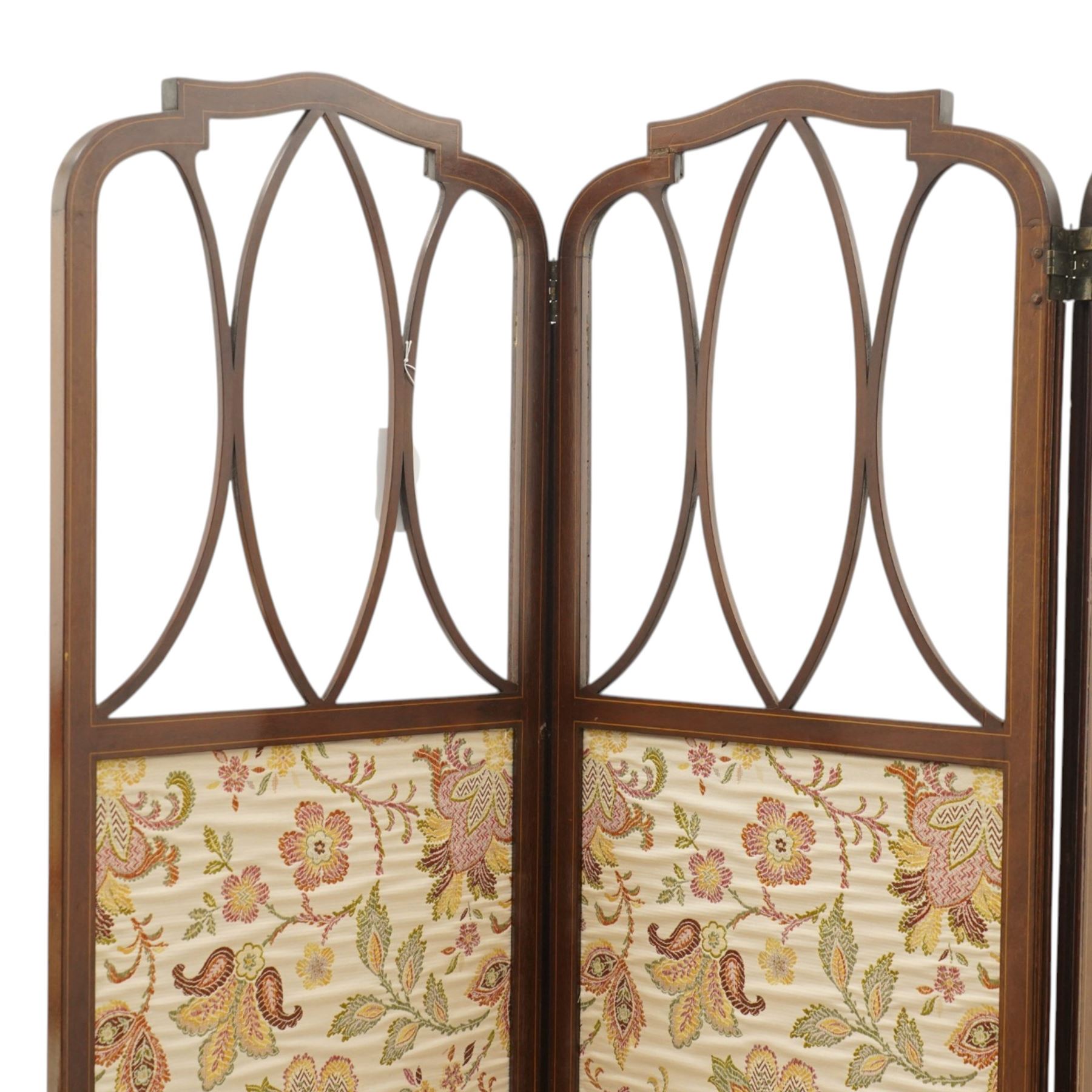 Edwardian inlaid mahogany three-fold screen, each panel with shaped cresting and satinwood line inlaid frame, with intersecting astragal bars, lower panels upholstered in floral fabric, hinged folding action on brass hinges