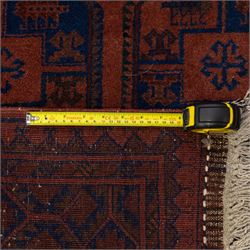 South East Persian Afshar hand-knotted rug, red ground decorated with a geometric design of octagonal medallions and incorporating stylized motifs in tones of indigo and dark brown within geometric borders, with fringe ends  