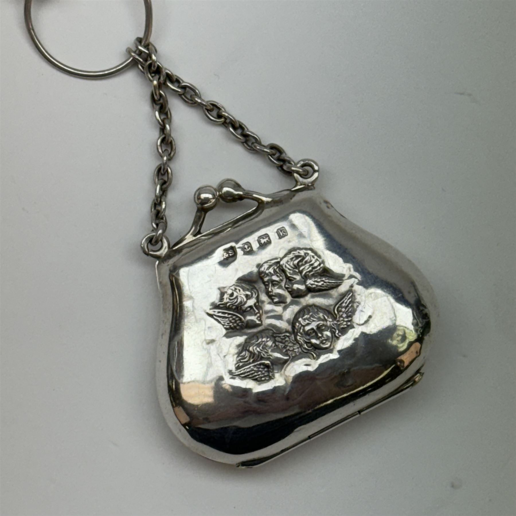 Victorian and later silver chatelaine, the shaped and foliate pierced clasp with embossed oval panel of a courting couple, hallmarked Levi & Salaman, Birmingham 1899, supporting six accessories on five chains: a circular mirror embossed with putti, hallmarked Henry Matthews, Birmingham 1911, pencil holder engraved with foliate scrolls, hallmarked Francis Webb, Birmingham 1914, conical scent bottle decorated with bamboo, (unmarked but testing as silver), aide memoire embossed with putti, hallmarked Samuel M Levi, Birmingham 1911, tape measure of compressed spherical form, hallmarked Henry Matthews, Birmingham 1899, and a purse with embossed putti, hallmarked Birmingham 1909, makers mark worn and indistinct, at longest point L31cm

