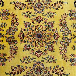 Persian Sarough hand-knotted carpet, golden yellow ground, with an all-over floral design centred by a small floral motif, the field decorated with mirrored flowering sprays, scrolling vines and dark navy foliate corner motifs, enclosed by a terracotta border with repeating flowerheads and palmettes, flanked by narrow guard stripes, with cotton fringes