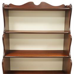 Early 20th century mahogany waterfall bookcase, shaped and serpentine side uprights with scalloped cresting, fitted with four open shelves above two short drawers with brass drop handles, raised on shaped bracket feet
