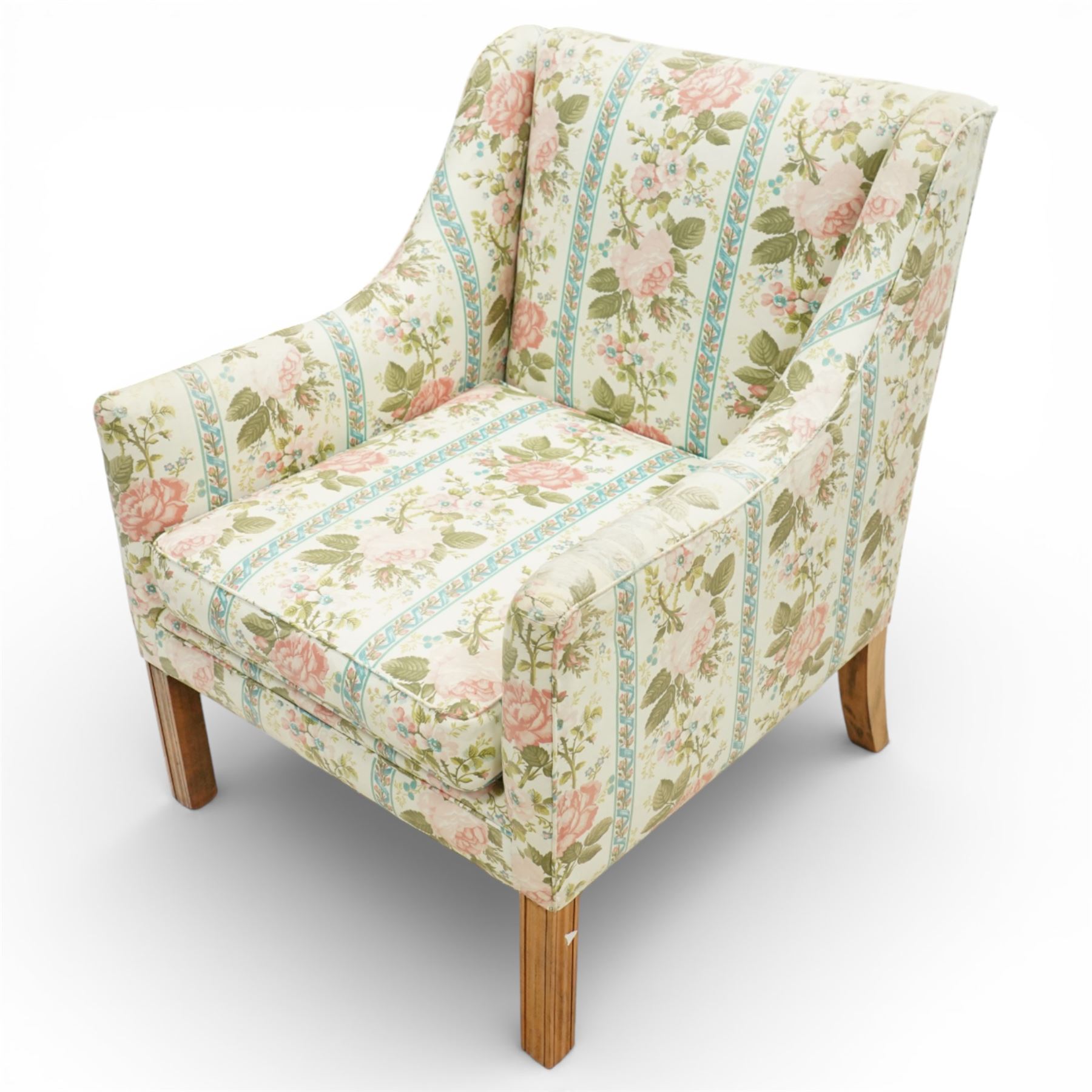 Pair of Edwardian upholstered armchairs, each with shaped padded back flanked by scroll arms, loose seat cushions, upholstered throughout in rose patterned fabric with vertical floral bands, raised on square tapering wooden legs