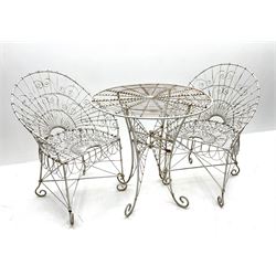 White painted scrolled wirework garden table (D77cm, H76cm), and two matching garden chairs