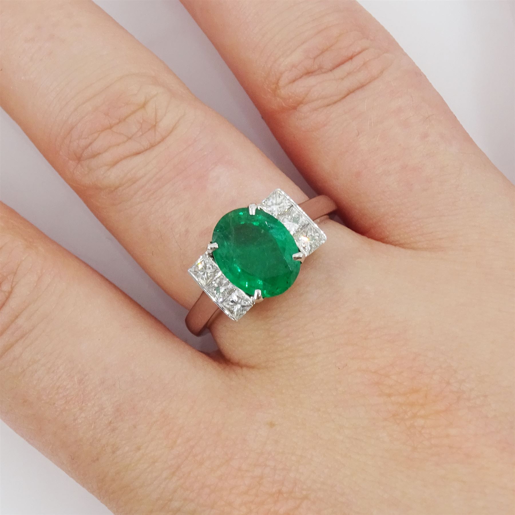 18ct white gold emerald and diamond ring, single oval cut emerald, each side set with three princess cut diamonds, stamped 750, emerald approx 1.90 carat, total diamond weight approx 0.50 carat