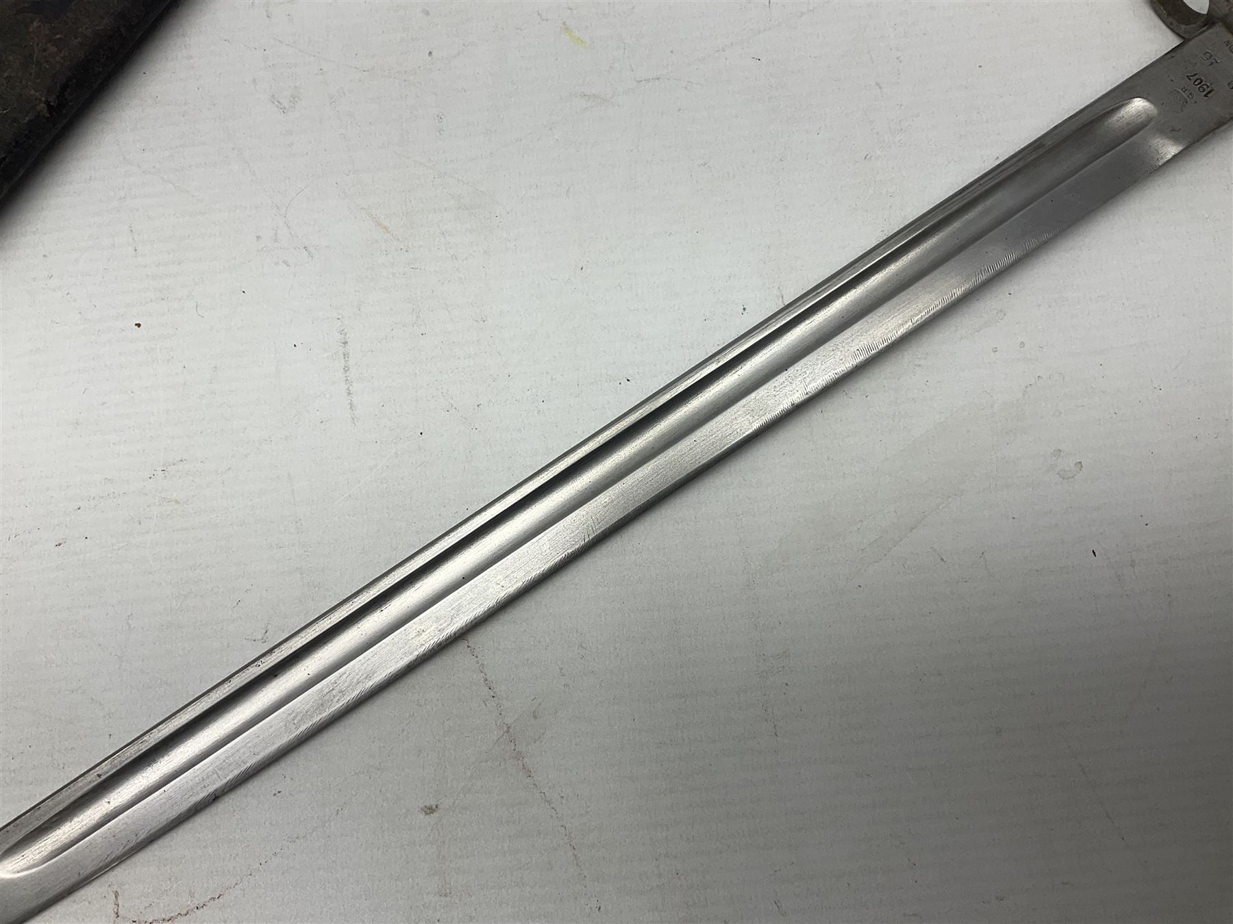 WW1 British 1907 pattern bayonet, the 43cm single edged fullered blade stamped to the ricasso with a crown GR cypher 1907 8 15 Sanderson, with various ordnance marks verso, two piece walnut grip, pommel stamped 1HLI 354; in steel mounted leather scabbard stamped 140 to the throat L57cm overall