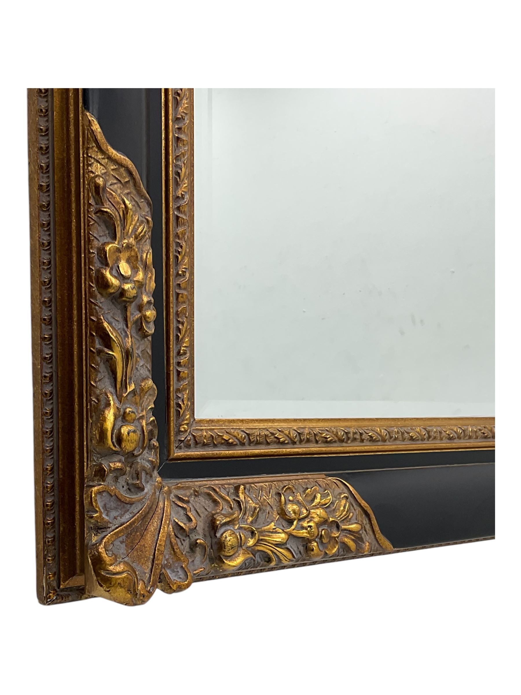 Early 20th century wall-hanging mirror, rectangular bevelled mirror plate within ebonised frame, gilt mounts to the corners carved with floral motifs 