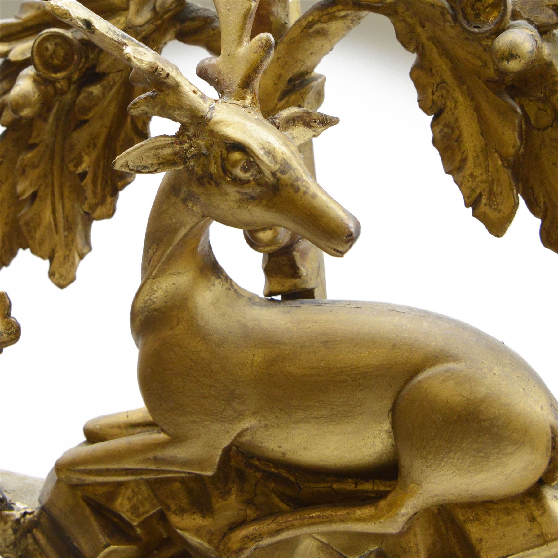 Regency gilt wood and gesso wall mirror, stag pediment with trailing oak leaves and acorns, extending curled acanthus leaves and fruiting vines, the convex mirror plate enclosed by rope twist and acanthus leaf decorated wreath