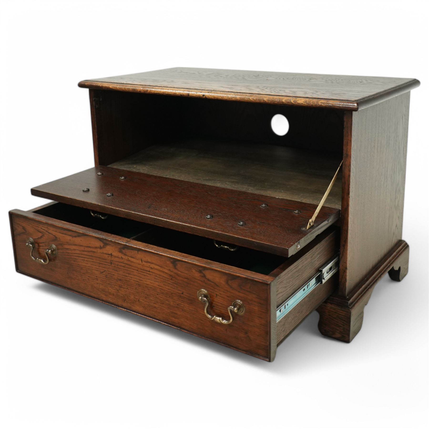 T & G style solid oak television cabinet, rectangular moulded top over two short and two long drawers with brass swing handles, the upper frieze drawer front hinged and fitted with stay to reveal pull-out shelf, open compartment above with circular cable aperture to rear, on bracket feet