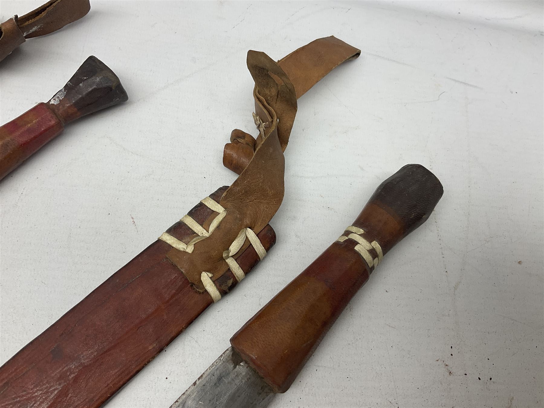 Indian kukri with 29cm curving steel blade and nickel mounted horn grip; in leather covered scabbard with one skinning knife L42cm overall; Hitler Youth knife with scabbard in relic condition; and three African graduated knives each with crudely carved wooden grips and painted leather covered scabbards (5)