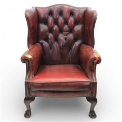 Georgian design wingback armchair upholstered in oxblood leather, the deep button upholstered back with shaped wings and out-scrolled arms, close nailhead trim to the edges, over a loose seat cushion, raised on cabriole front supports terminating in claw and ball feet