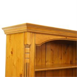 Late 20th century traditional waxed pine open bookcase, moulded cornice above a shaped frieze, open front with fixed shelves and boarded back, flanked by fluted pilasters