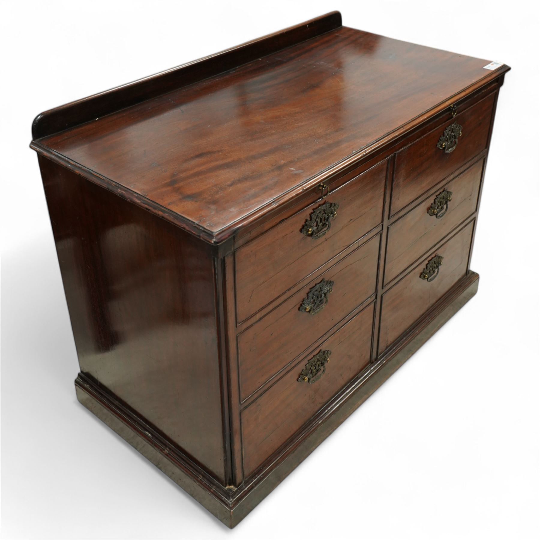 Early 20th century mahogany chest, rectangular top with raised gallery back with brushing slide on sliding tray, fitted with two cupboard doors behind six false drawer fronts, pierced brass handles on a plinth base