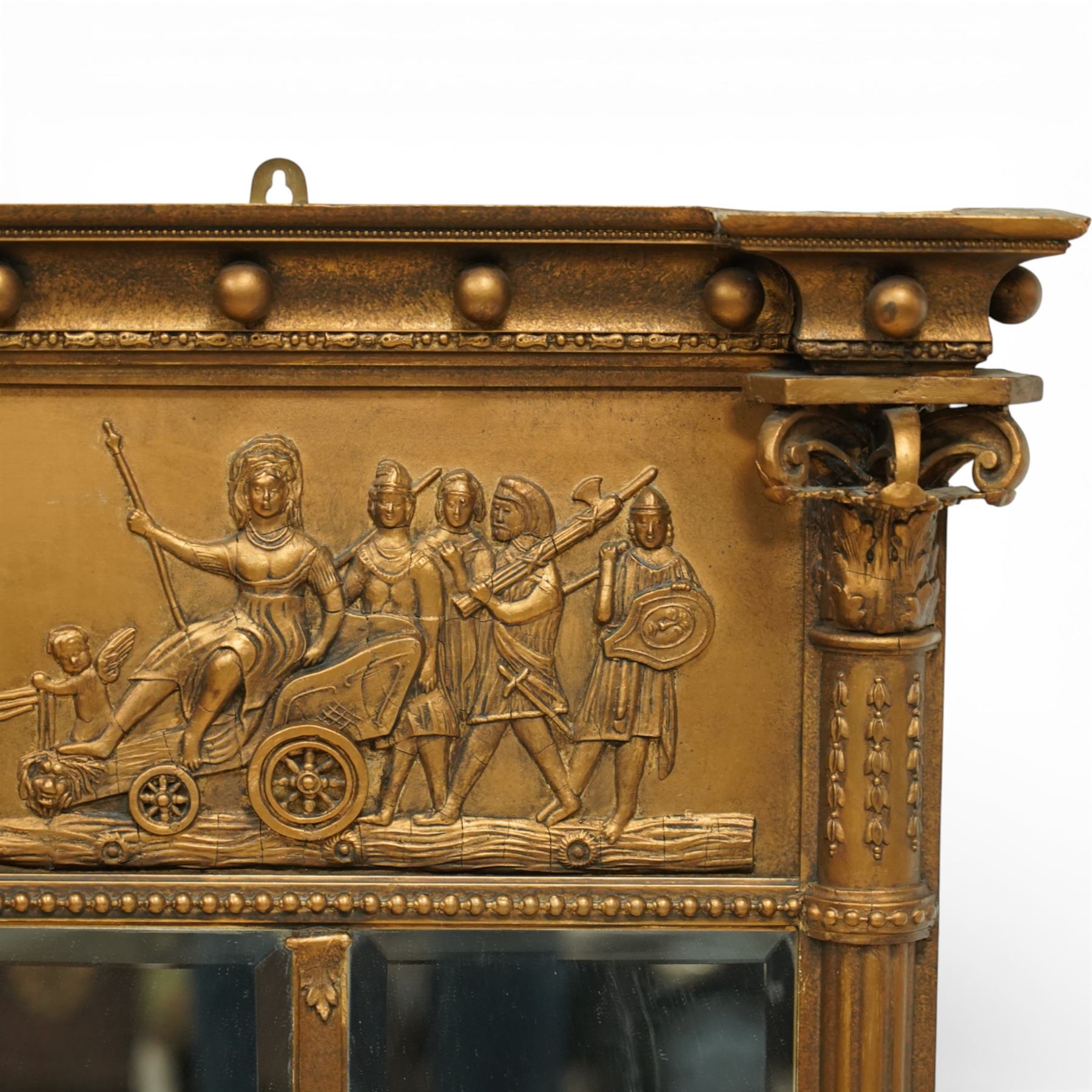 Early 20th-century giltwood tripartite overmantel mirror, rectangular frame with ball decorated cornice above frieze decorated with a classical allegorical depiction of the Triumph of Cybele in a processional chariot drawn by lions, above a beaded moulding and rectangular mirror plate, flanked by plain and reeded pilasters with Corinthian capitals, shafts decorated with pendant garlands  