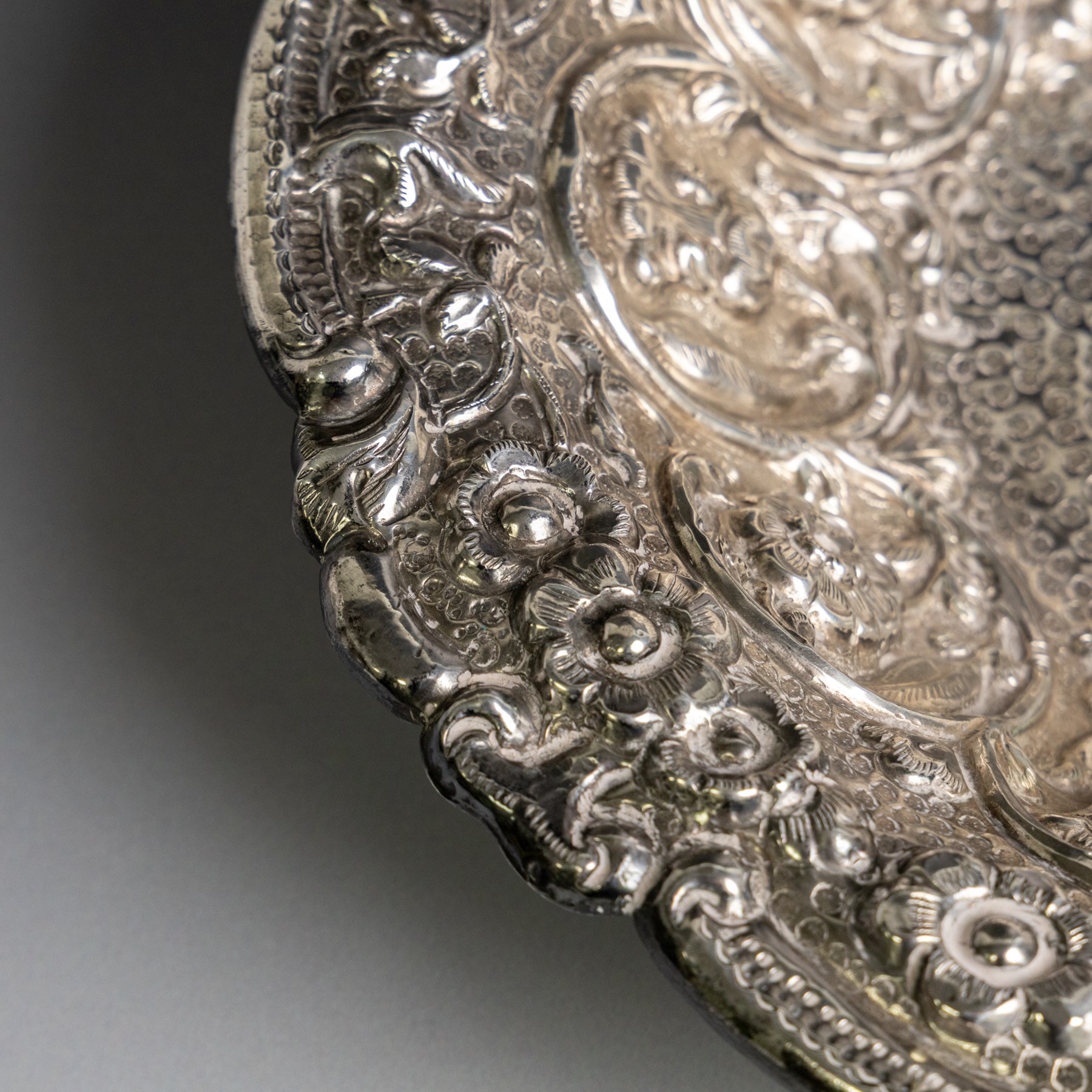 Late 19th/early 20th century continental silver serving bowl, of oval form, profusely embossed with scrolling floral and foliate decoration, with hammered finish to interior