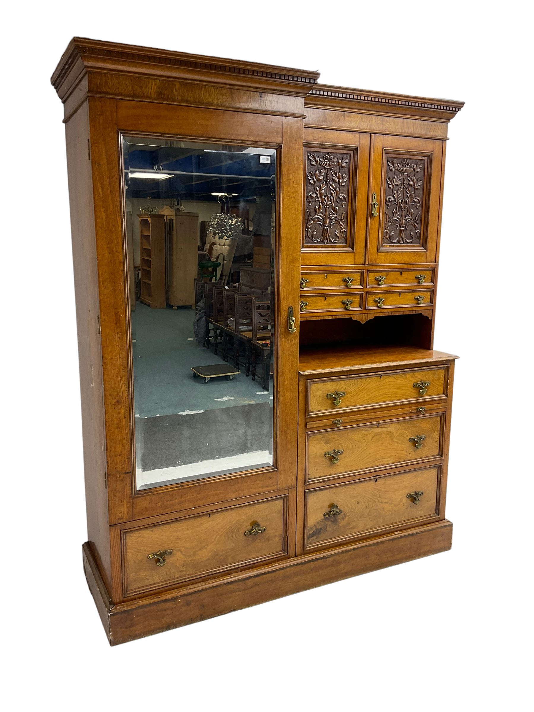 Victorian figured oak and pollard oak combination wardrobe, projecting dentil cornice, the left hand side enclosed by large bevelled mirror glazed door over drawer, the interior with sliding hanging rail, the right hand side with cupboard enclosed by two panelled doors relief carved with urn and trailed trailing foliage, four small drawers over shelf, three drawers and brushing slide, the slide with tooled and gilt blue leather inset, plinth base