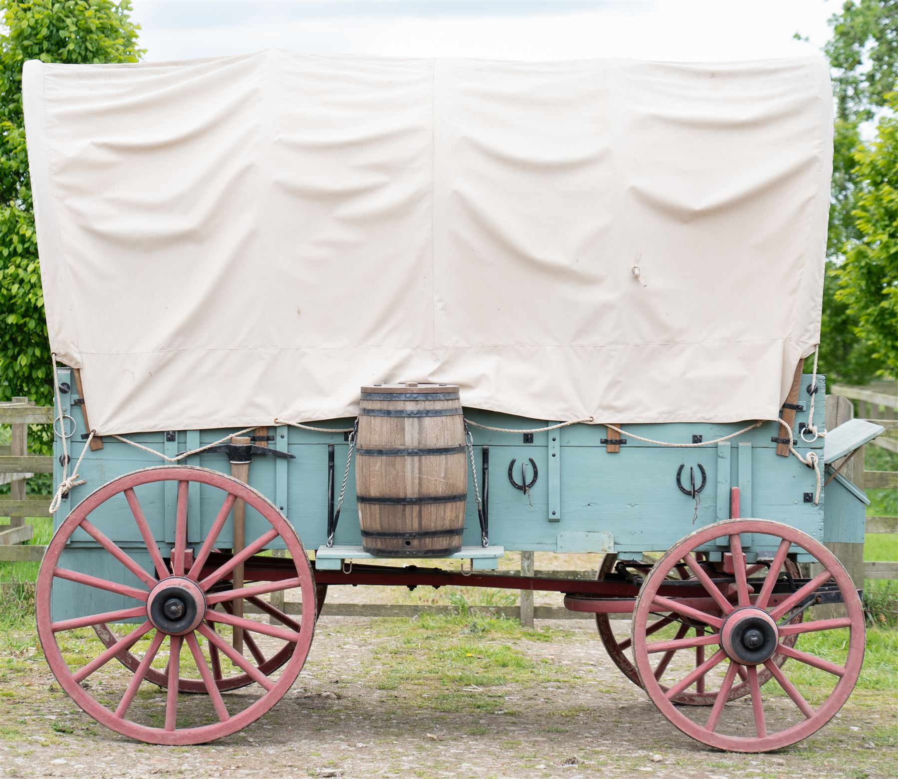 Western Covered Chuck Wagon

A large four wheeled covered wagon of timber construction, painted pale green with red painted wooden spoked wheels and a cream canvas tilt over an arched frame. The wagon has a traditional box body with covered rear compartment, front driving position, underbody turntable steering and iron fittings throughout. Fitted with external equipment details including a side mounted barrel, lidded storage chest, rope tie downs, horseshoe fittings and rear storage box.

Features

• Pale green painted timber body
• Cream canvas tilt over arched frame
• Covered rear compartment
• Front driving position
• Side mounted barrel
• External lidded storage chest
• Rear storage box
• Wooden spoked wheels
• Iron tyres
• Underbody turntable steering
• Rope tie downs
• Horseshoe fittings
• Iron hardware and brackets
• Brass restoration plaque to rear

Dimensions:
Overall length: 335 cm
Width: 170 cm
Height: 275 cm

Wheel Diameters:
Front wheels: 92 cm
Rear wheels: 112 cm

Seating:
Driver: 1
Passenger: Rear covered compartment