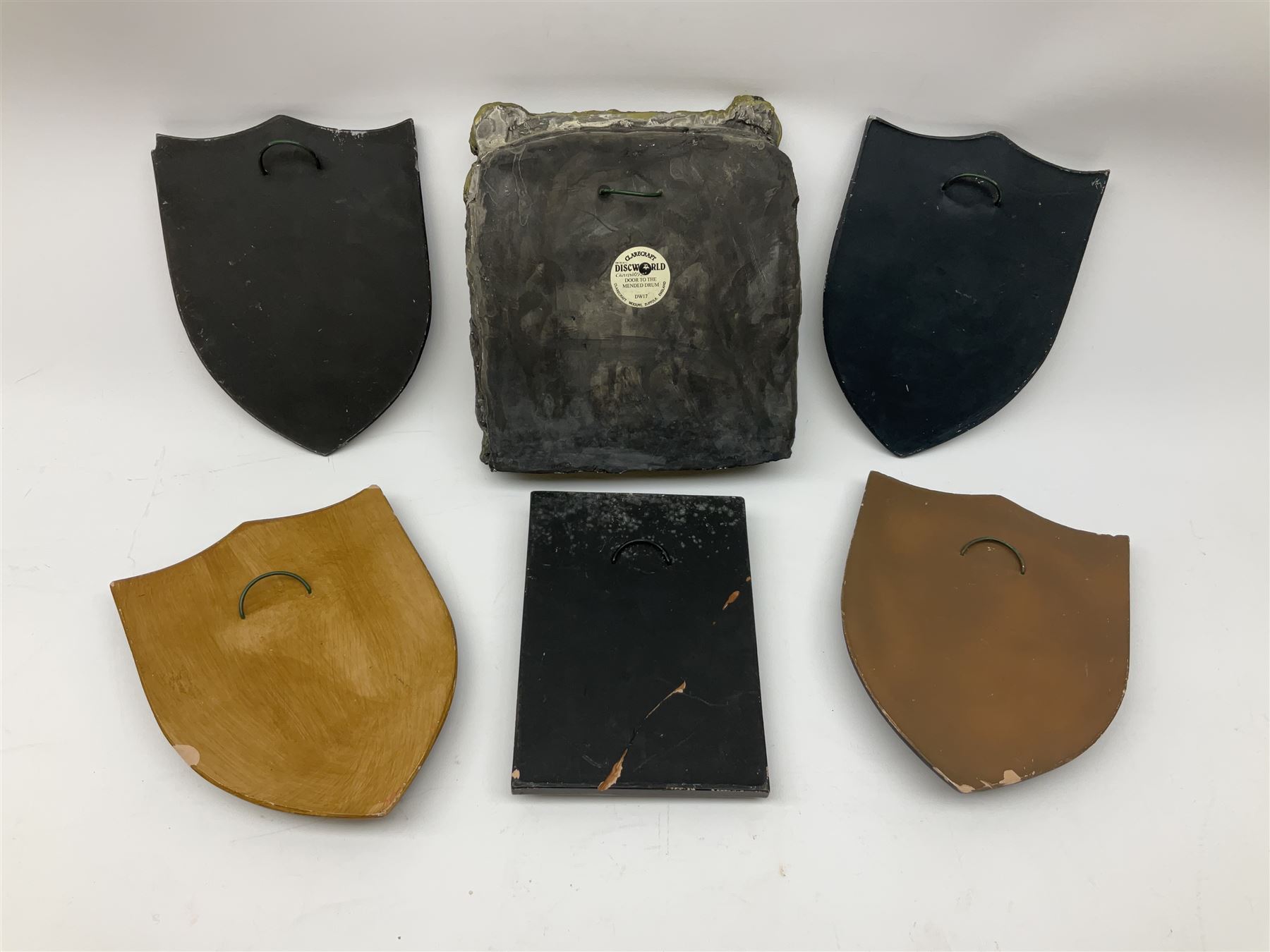 Terry Pratchett Discworld plaques, designed by Clarecraft, comprising 'the First Discworld Event Clarecraft August 95', the collectors guild joining shield, the fools guild DW99C, the seamstresses guild DW98C, the musicians guild DW00C together with 'Door of the mended drum' wall hanging DW17. 