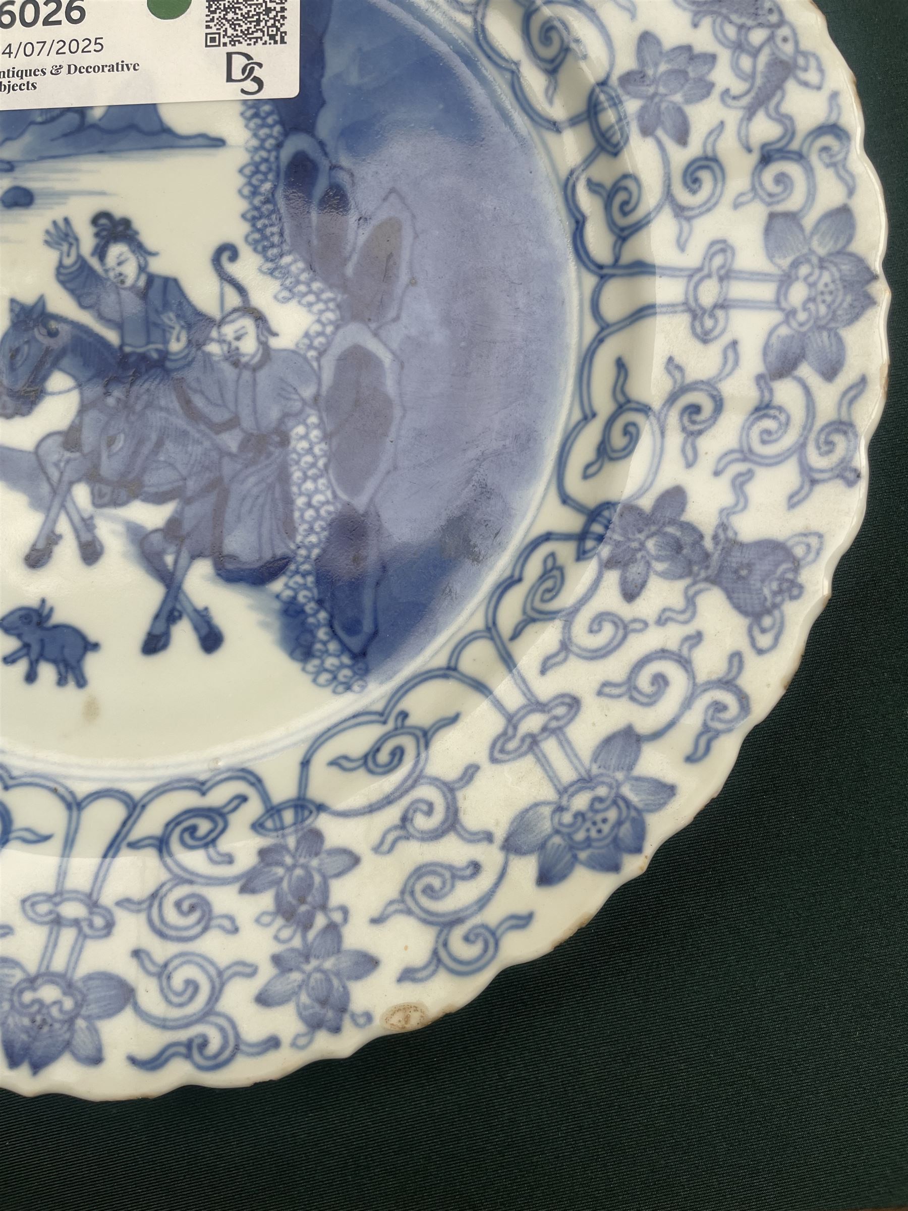 Chinese Kangxi style blue and white plate, decorated to the centre with a hunting scene  of two hunters on horse back, surrounded by a foliate boarder, with with six character double ring mark beneath