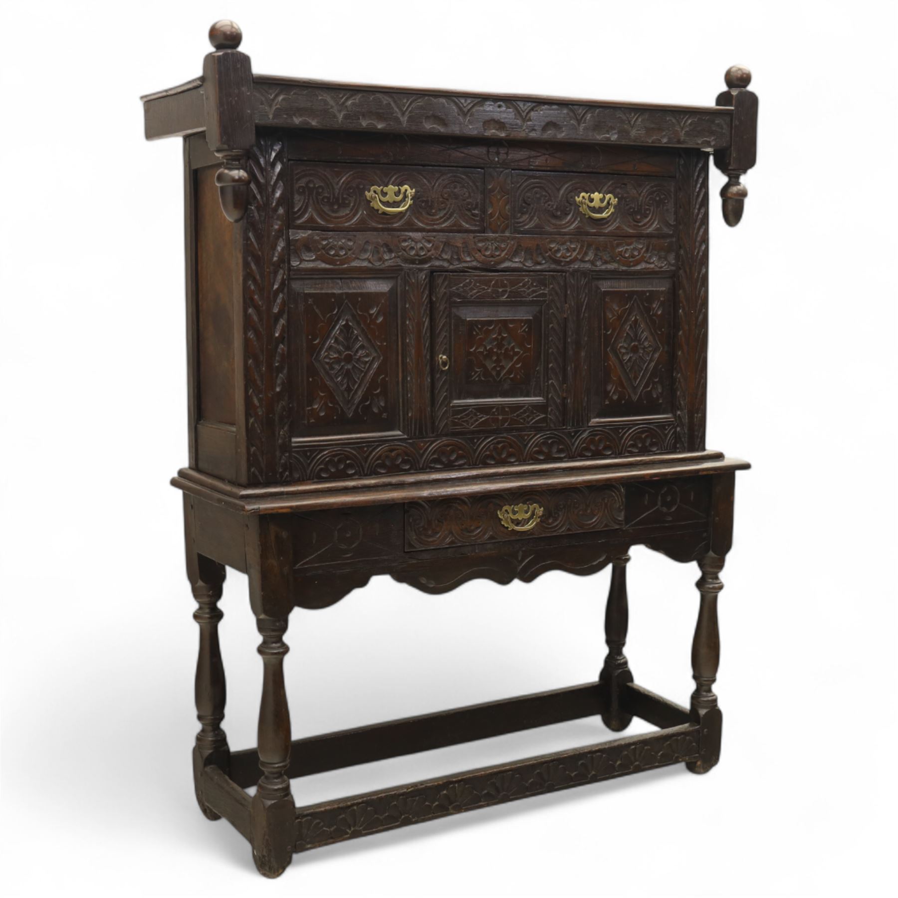 19th century and later carved oak court cupboard, the upper section with two drawers above a central cupboard door flanked by panels, lower section with single long drawer, on turned supports united by carved stretchers