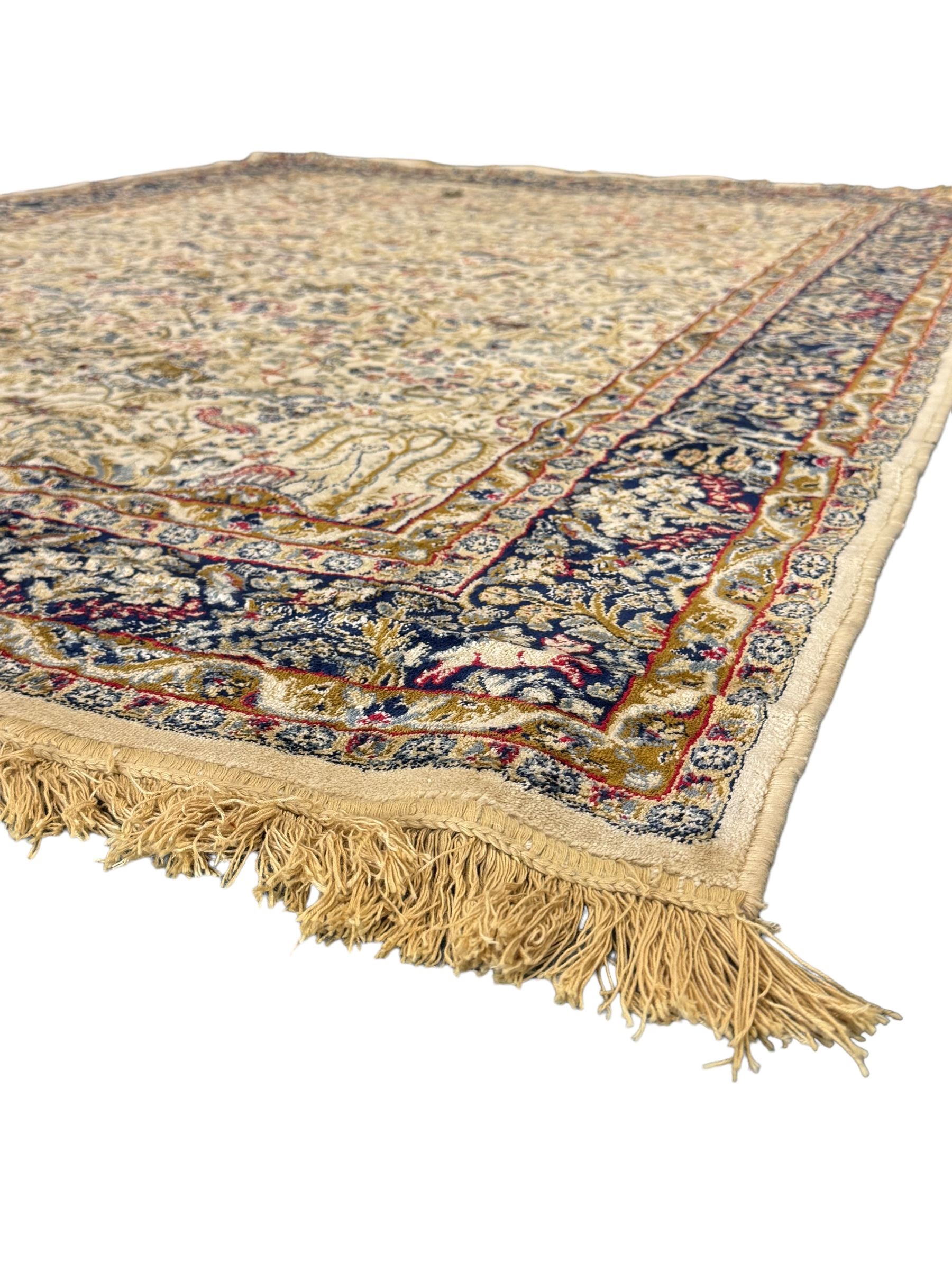 Persian Kerman ivory ground rug, the field adorned with naturalistic depictions of birds, animals and floral designs, framed by a multi-band border in blue and red tones
