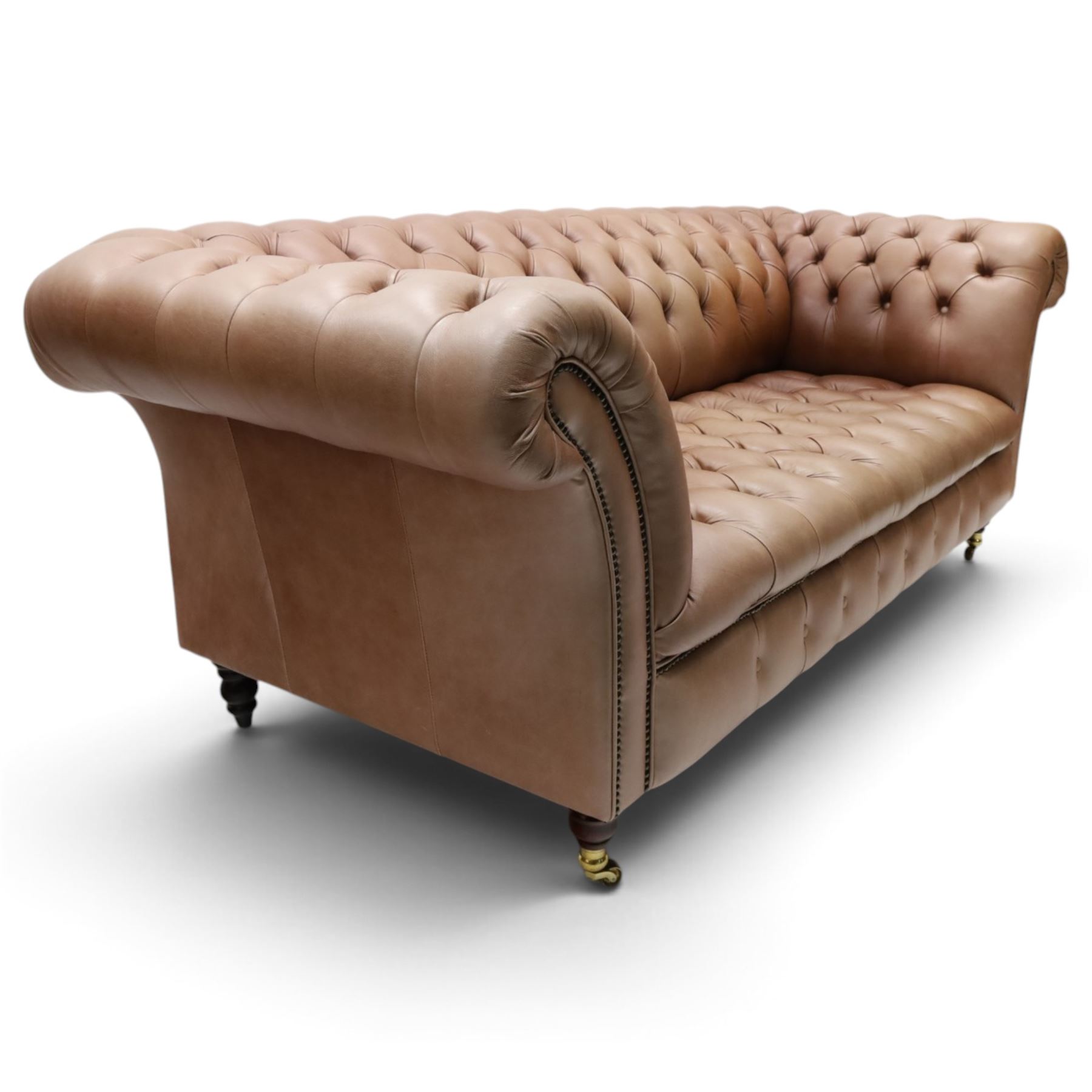 Distinctive Chesterfield - full buttoned tan brown leather sofa, deep buttoned back, seat and arms, raised on dark stained supports terminating in brass castors 