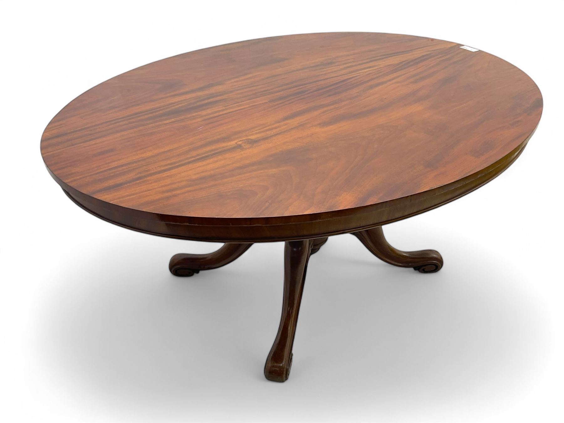 Victorian mahogany breakfast loo table, oval tilt-top on turned pedestal, quatrefoil out-splayed carved supports, scroll carved terminals with brass castors